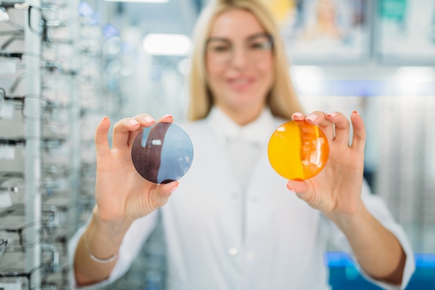 Ótica mostra lentes de diferentes cores, vitrine com óculos em loja de ótica