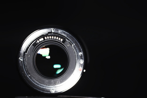Foto Ótica para a câmera na mesa do operador. flare no vidro de uma lente fotográfica. fundo preto com a técnica do fotógrafo.