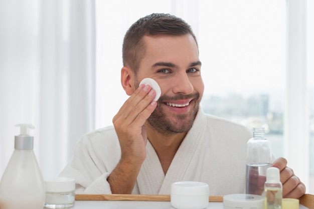 Ótimo humor. Homem alegre e simpático sorrindo para você enquanto limpa a pele