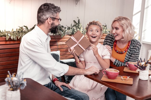 Ótimo humor. menina alegre e animada sorrindo enquanto celebra seu aniversário com a família