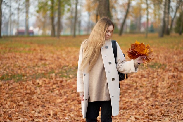 Otoño. Alegre joven muy elegante con largo cabello rubio vistiendo abrigo de otoño moderno