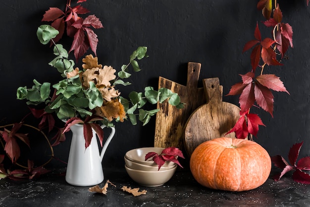 Otoño cocina bodegón Vajilla jarra con ramas de eucalipto tablas de cortar vid corona calabaza