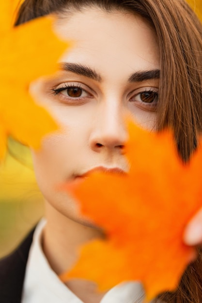 Otoño colorido retrato de mujer hermosa con cara bonita con hojas doradas en el parque