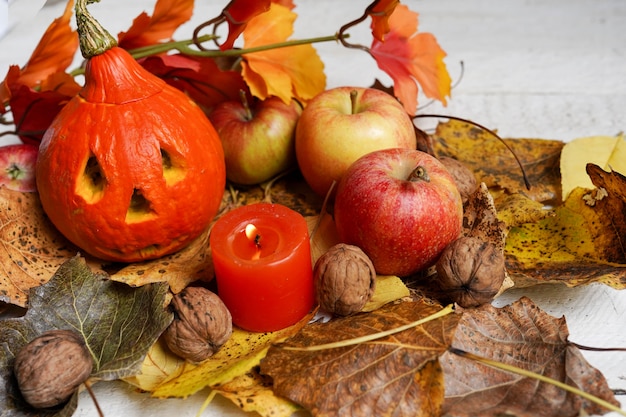 Otoño composición de halloween con hojas, manzanas y calabaza con cara