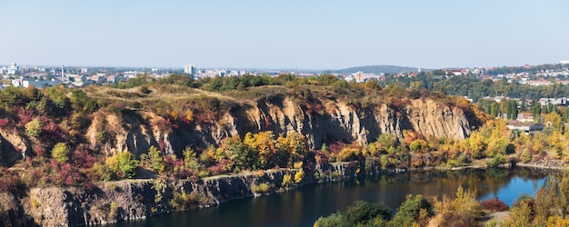 Otoño dorado con árboles de colores en la antigua cantera inundada. Rocas, lago y árboles amarillos