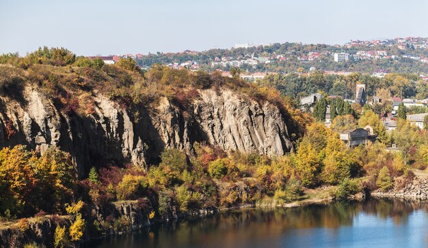 Otoño dorado con árboles de colores en la antigua cantera inundada. Rocas, lago y árboles amarillos