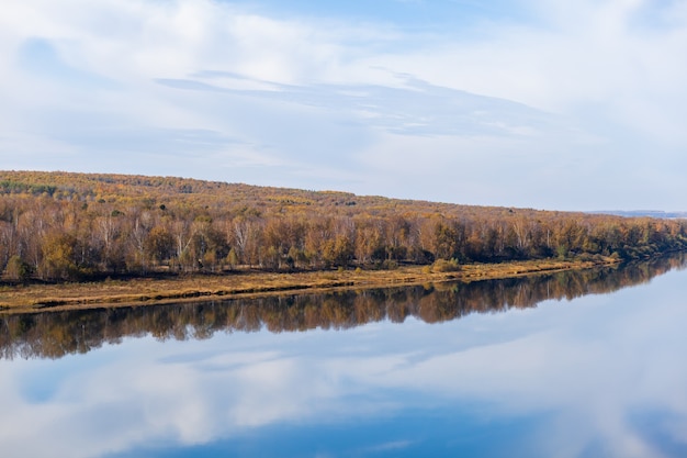 Otoño hermoso y ancho río entre los bosques. Lugar tranquilo y silencioso con colores otoñales. En medio de la isla fluvial. Vista desde arriba a la distancia