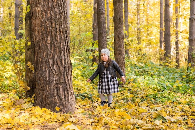 Otoño, infancia, concepto de personas - niña feliz caminando en el parque de otoño.