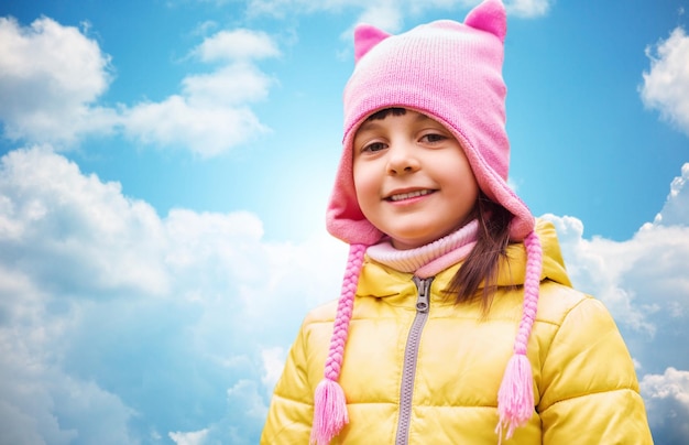 El otoño, la infancia, la felicidad y el concepto de la gente - feliz y hermoso retrato de niña al aire libre sobre el cielo azul y el fondo de las nubes