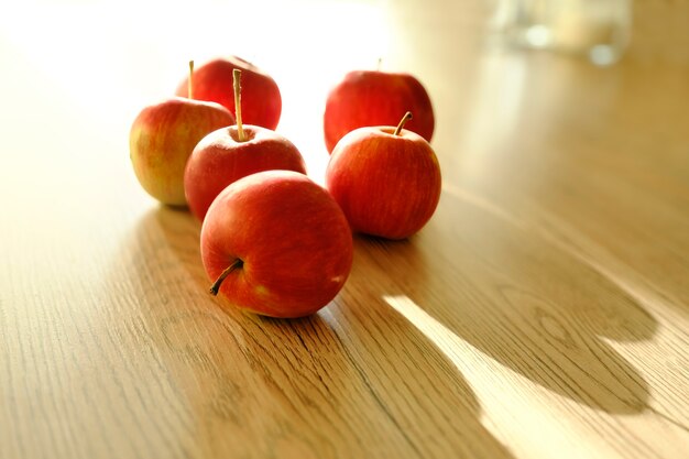 Otoño de manzanas rojas sobre una mesa de madera iluminada por la luz del sol