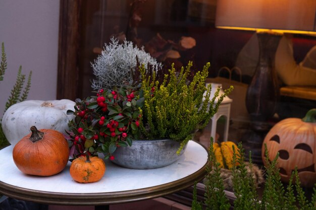 Otoño muestra la entrada a la tienda decorada con flores y una calabaza para la noche de Halloween