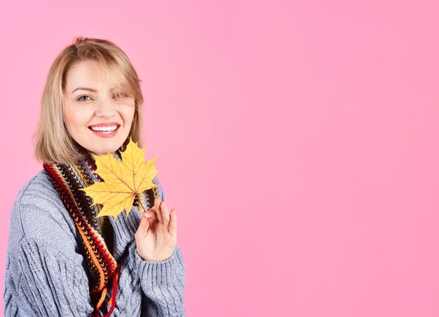 Otoño. Mujer con hoja de otoño. Mujer sonriente con hoja otoñal. Otoño. Estado de ánimo de otoño. Mujer en suéter caliente tiene pan de oro. Ropa calida. Venta de temporada. Descuento. Venta. Copie el espacio.