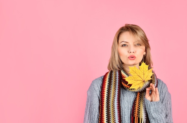 Otoño. Mujer sensual con hoja de arce. Mujer con hoja de otoño. Hoja de arce amarilla. Mujer sexy en ropa de abrigo tiene hoja de arce. Aislado. Estado de ánimo de otoño. Hojas de otoño.