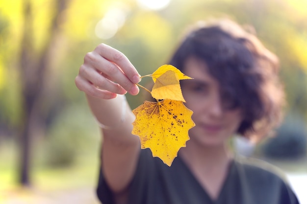 Foto otoño - niña sostiene una hoja amarilla