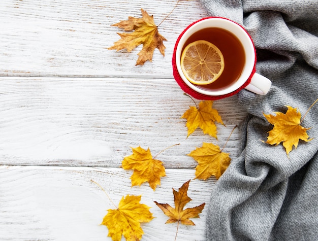 Otoño plano con taza de té y hojas.