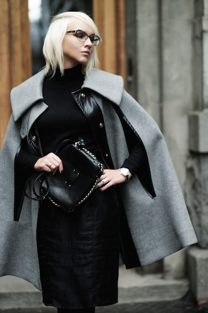 Otoño retrato de hermosa mujer rubia en abrigo gris con bolso negro