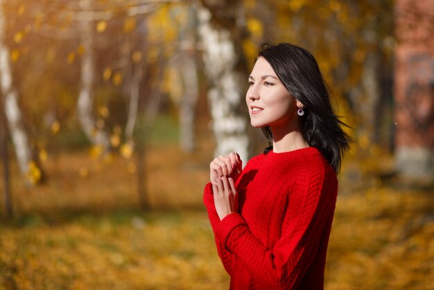 Otoño retrato de una joven mujer morena en un suéter rojo