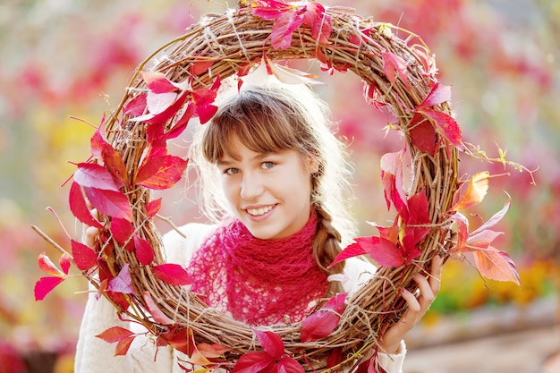Otoño retrato de niña adolescente. Chica bonita adolescente con hojas de parra roja en el parque de otoño.