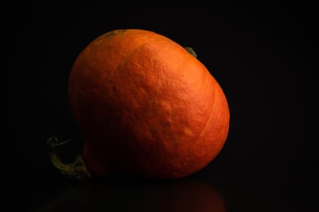 Otoño rojo Kuri o pumkpin naranja sobre un fondo negro. Foto de concepto de comida vegetal fresca