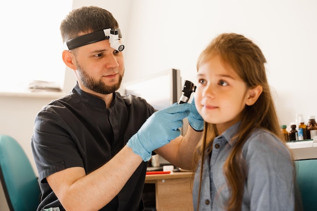 Otorrinolaringologista com otoscópio Otoscopia Pediatra otorrinolaringologista olha através do otoscópio os ouvidos da criança Otoscopia Tratamento dor de ouvido