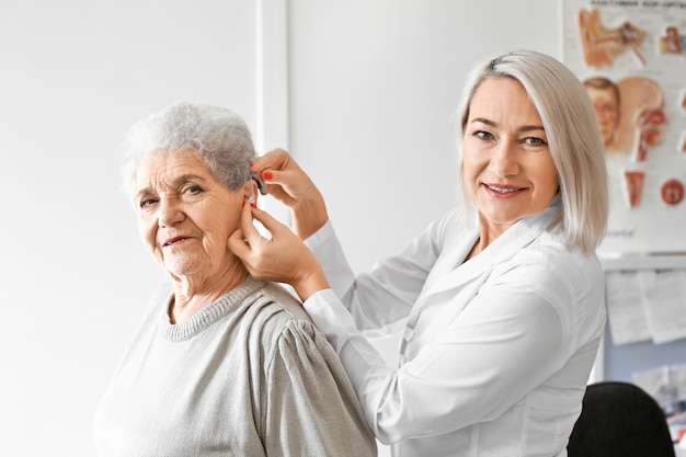 Otorrinolaringólogo poniendo audífonos en el oído de la mujer mayor en el hospital