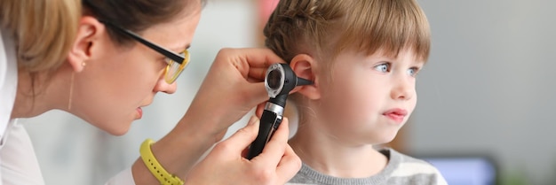 Foto otorrinolaringólogo realiza un examen físico de la oreja de la niña
