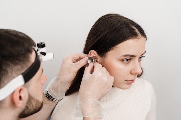 Otoscopia de oídos con embudo de oído Otorrinolaringólogo con otoscopio Consulta con otorrinolaringólogo Tratamiento del dolor de oído de la mujer