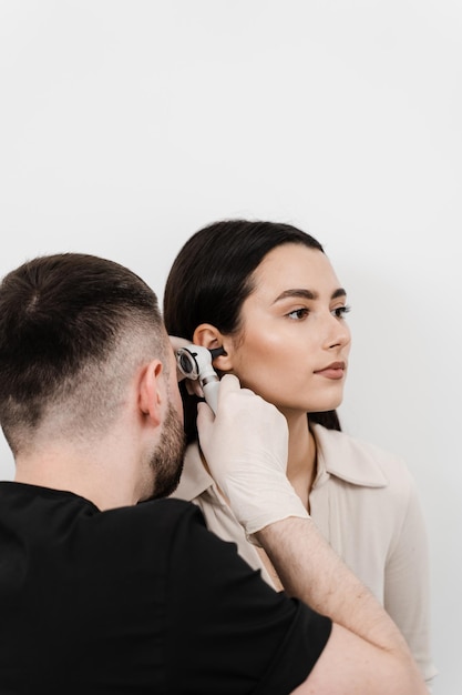 Otoscopía El otorrinolaringólogo está mirando a través del otoscopio los oídos de la mujer Tratamiento del dolor de oído Otorrinolaringólogo con otoscopio de oído