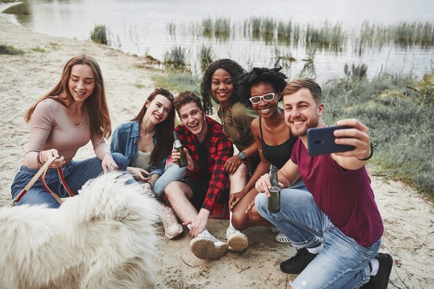 Otro selfie. Grupo de personas tienen picnic en la playa. Los amigos se divierten los fines de semana.