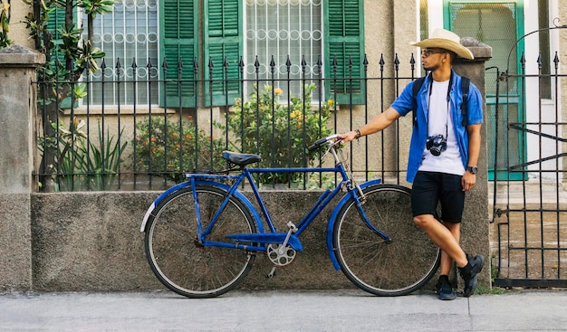 Ourist em pé na rua ao lado de um conceito de viagem de bicicleta azul