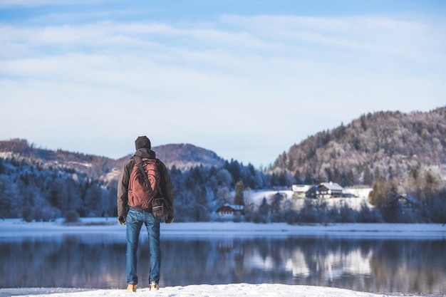 Outdoor-Abenteuer Kaukasischer Mann steht am Seeufer und genießt die Aussicht Schöne Winterlandschaft Österreich