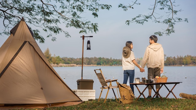 Outdoor-Aktivitätskonzept Junges Paar Rucksacktouristen campen und halten Händchen mit glücklichen Menschen in der Nähe des Sees