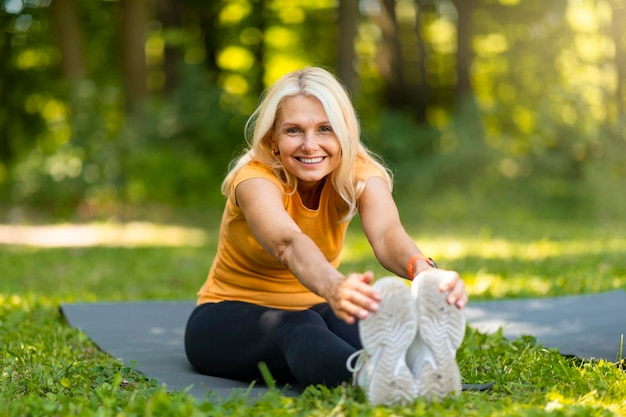 Outdoor-Fitness-Porträt einer schönen älteren Frau, die die Beinmuskulatur ausdehnt