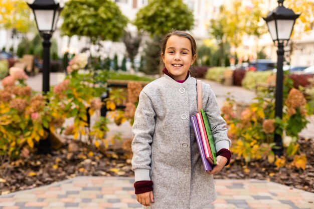 Outdoor-Herbstporträt eines glücklich lächelnden Mädchens, das stilvolles Outfit mit Lederrucksack trägt und in der Straße der Stadt posiert