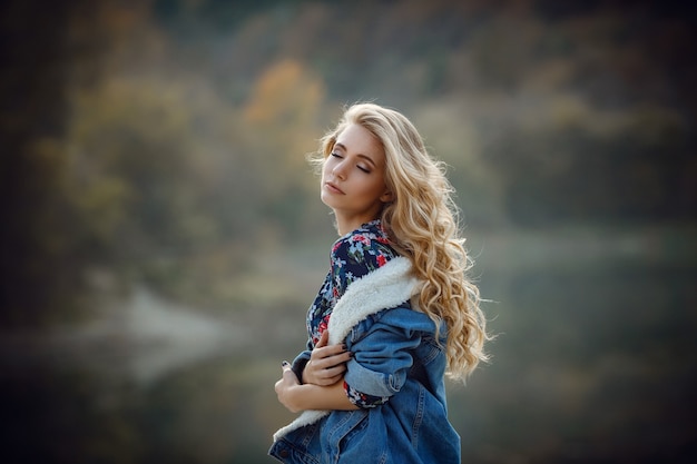 Outdoor-Herbstporträt von Mädchen mit Hut und Jeans tragen. Naturhintergrund, ländliche Landschaft, Landhausstil nahe einem See im Wald