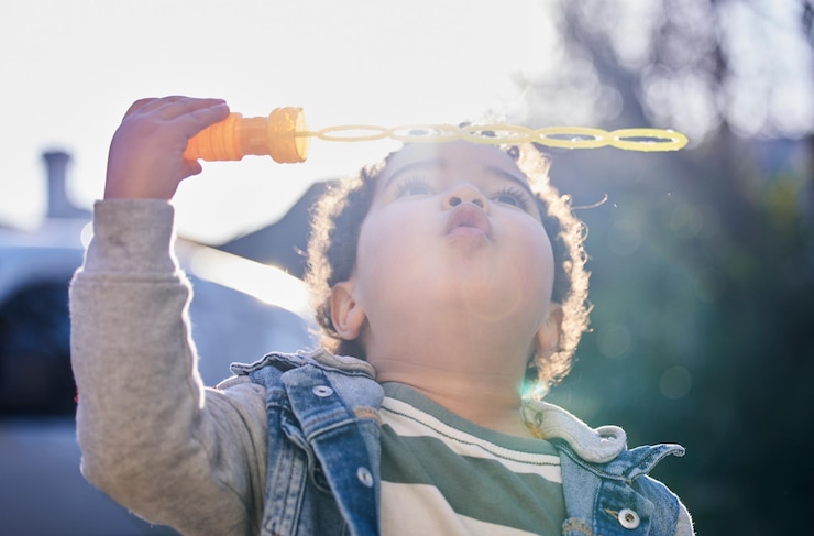 Foto outdoor-junge und spielen mit blasmaschine für spaß wachstum und genießen im park oder garten sommer kind und entspannen auf der pause mit kindentwicklung für spiele in der natur mit sonnenschein zu kühlen mit spielzeug