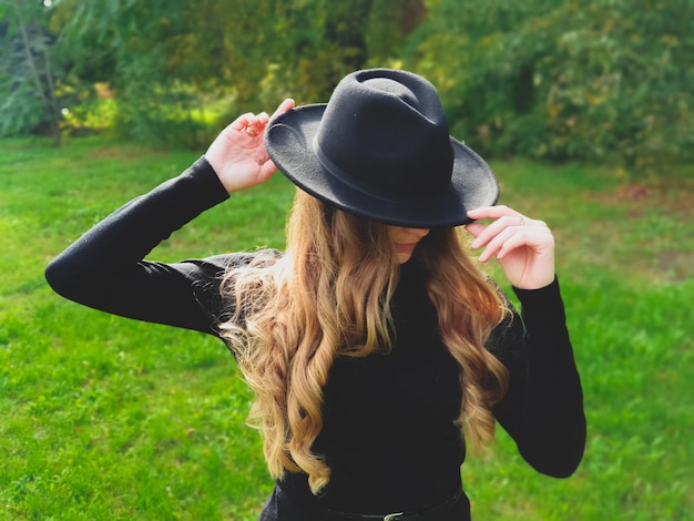 Outdoor-Lifestyle-Modefoto schöne Dame im Park mit schwarzem Hut und Pullover warmer Herbst