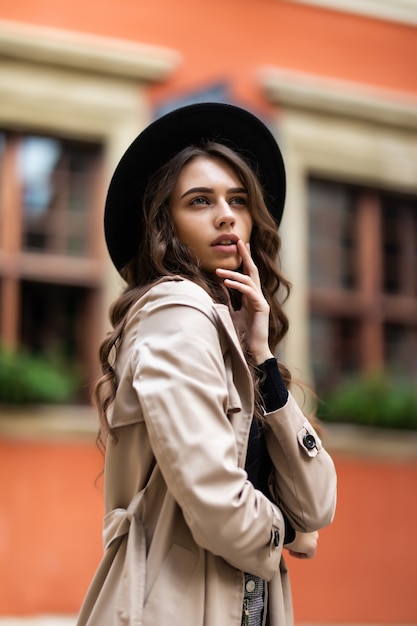 Outdoor-Mode-Porträt der sinnlichen jungen stilvollen Dame des Glamours, die trendiges Herbstoutfit und schwarzen Hut auf der Straße trägt