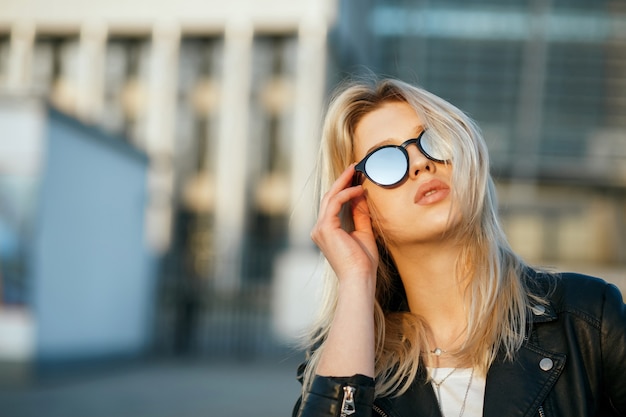 Outdoor-Mode-Porträt einer modischen blonden Frau mit Spiegel-Sonnenbrille. Platz für Text