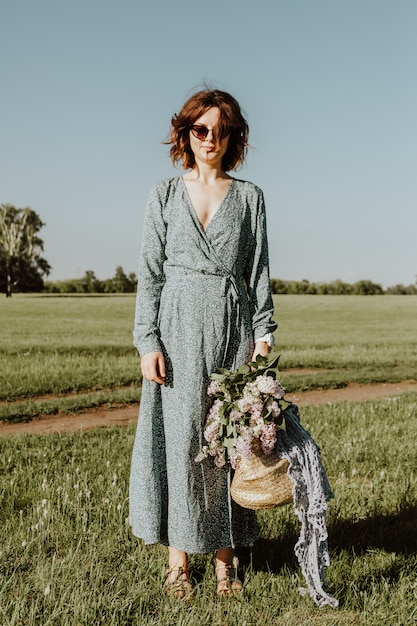 Outdoor-Modeporträt der jungen Frau der Schönheit in einem hellblauen Kleid, das auf Sommerpark geht. Sommerkleidung und Accessoires.