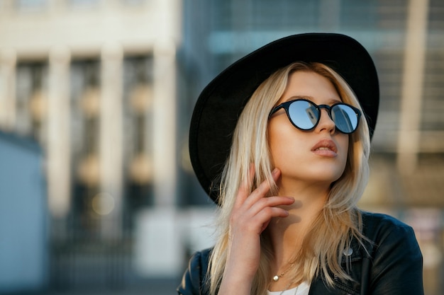 Outdoor-Modeporträt einer schönen blonden Frau mit Hut und Spiegelsonnenbrille. Platz für Text