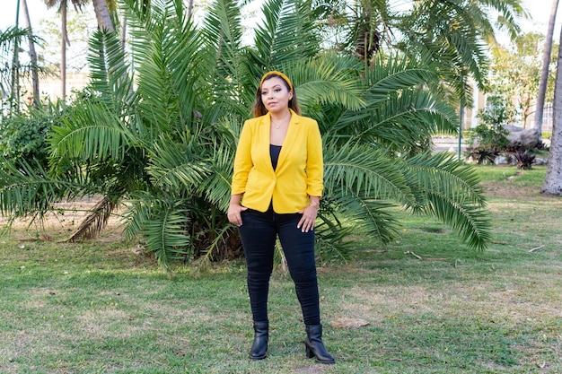 Outdoor-Porträt der Frau in der gelben Jacke Portrait der jungen mexikanischen Frau in einem Garten bei Sonnenuntergang