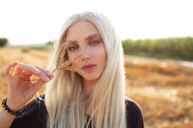 Outdoor-Porträt des jungen blonden Mädchens mit Weizenspitzen, auf dem Gebiet.