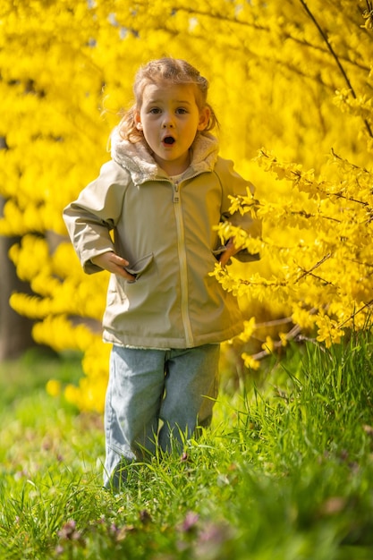 Outdoor-Porträt des kleinen Mädchens vor Forsythia-Busch im Prager Park Europa