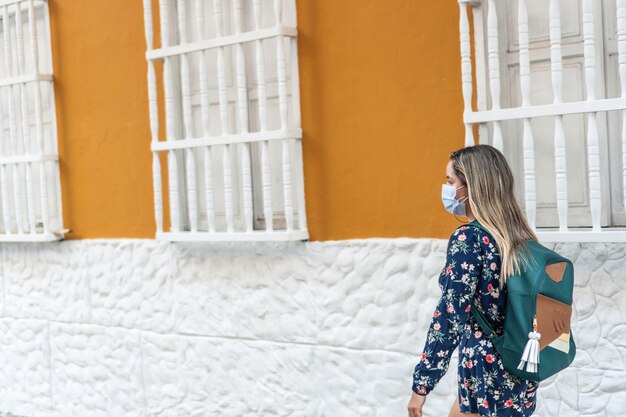 Outdoor-Porträt einer jungen Latina-Frau mit Schutzmaske, die während des Ausbruchs des Coronavirus durch die Stadt spaziert.