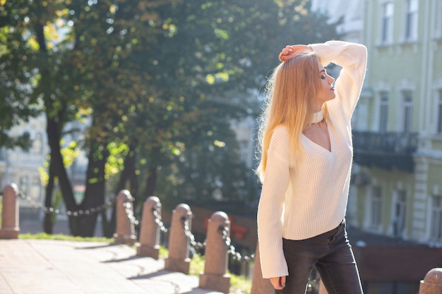 Outdoor-Porträt eines entzückenden Modells mit stilvollem Outfit, das mit natürlichem Sonnenlicht auf der Straße posiert. Freiraum