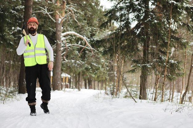 Outdoor-Porträt eines gutaussehenden Mannes in Mantel und Schal. Bärtiger Mann im Winterwald.