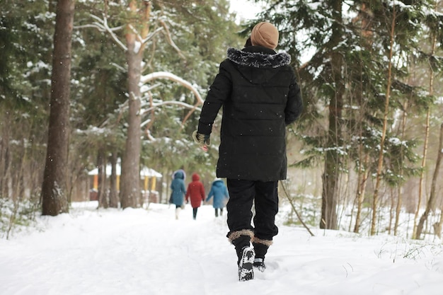 Outdoor-Porträt eines gutaussehenden Mannes in Mantel und Schal. Bärtiger Mann im Winterwald.