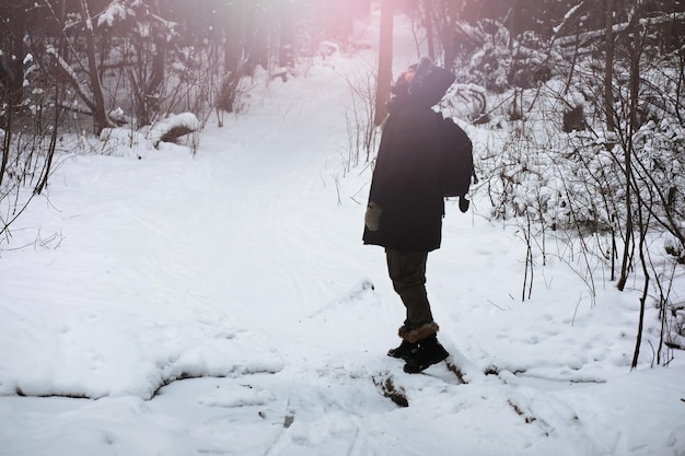 Outdoor-Porträt eines gutaussehenden Mannes in Mantel und Schal. Bärtiger Mann im Winterwald.