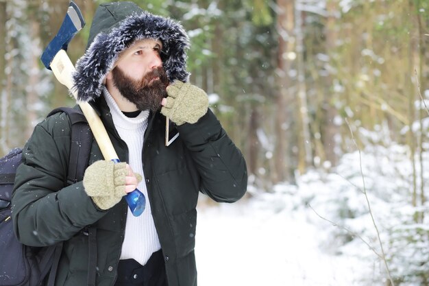 Outdoor-Porträt eines gutaussehenden Mannes in Mantel und Schal. Bärtiger Mann im Winterwald.